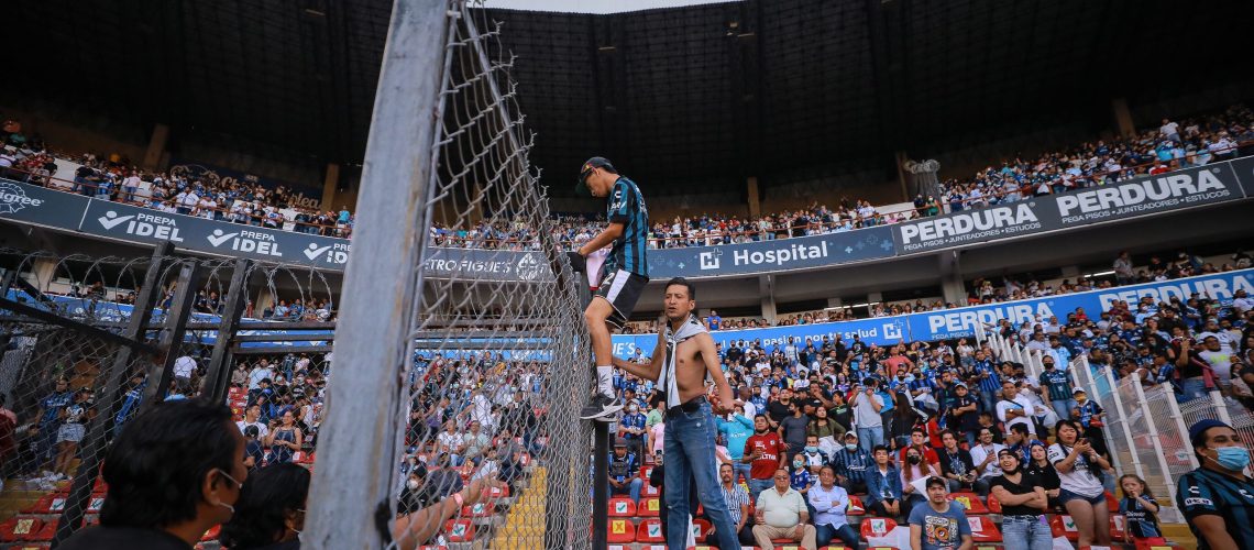 QUERETARO, MEXICO - MARCH 05: Fans climb a the wire fence to enter the field during the 9th round match between Queretaro and Atlas as part of the Torneo Grita Mexico C22 Liga MX at La Corregidora Stadium on March 05, 2022 in Queretaro, Mexico. The match was suspended on the 60th minute due to violent fights between fans resulting in many injured. (Photo by Manuel Velasquez/Getty Images)